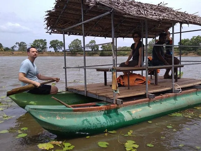 turistas relajándose en un catamarán básico con techo de paja en el agua