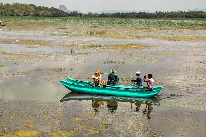 Touristen und Einheimische in einem kleinen grünen Boot auf einem flachen See